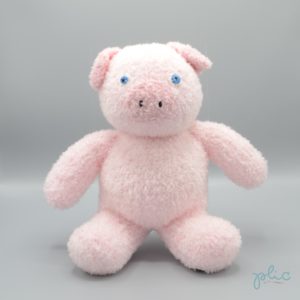 Peluche de 30cm de haut représentant un petit cochon, tricotée par Plic.