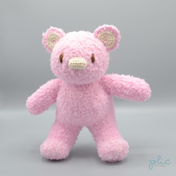 Peluche de 30cm de haut représentant un ourson rose pâle, tricotée par Plic.