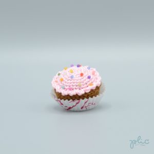 petit gâteau de 4cm de haut, recouvert d'un disque rose pâle crocheté par Plic et décoré de perles colorées.