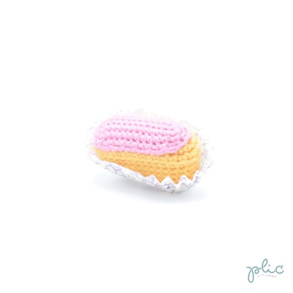 mini éclair au crochet de 6cm de long, recouvert d'une bande rose crochetée, le tout réalisé par Plic.