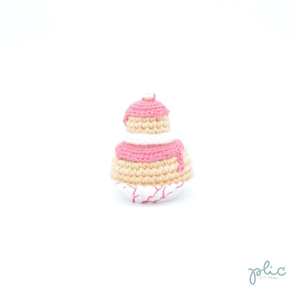 Petit gâteau de 6,5cm de haut, composé de 2 choux crochetés superposés, recouverts de disques rose moyen crochetés, d'un tour blanc au tricotin et d'une perle nacrée, le tout réalisé par Plic.