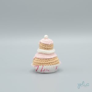 petit gâteau de 6,5cm de haut, composé de 2 choux crochetés superposés, recouverts de disques rose pâle crochetés, d'un tour blanc au tricotin et d'une perle nacrée, le tout réalisé par Plic.