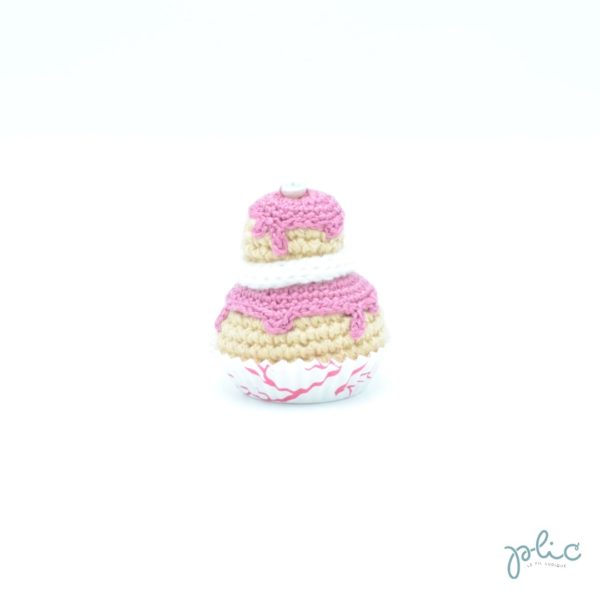 petit gâteau de 6,5cm composé de 2 choux de grandeur différente réalisés au crochet, recouverts de disques rose foncés crochetés, d'un tour blanc au tricotin et d'une perle nacrée, le tout réalisé par Plic.